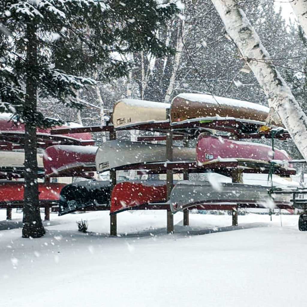 The snow falling on upside down canoes in wintetime.
